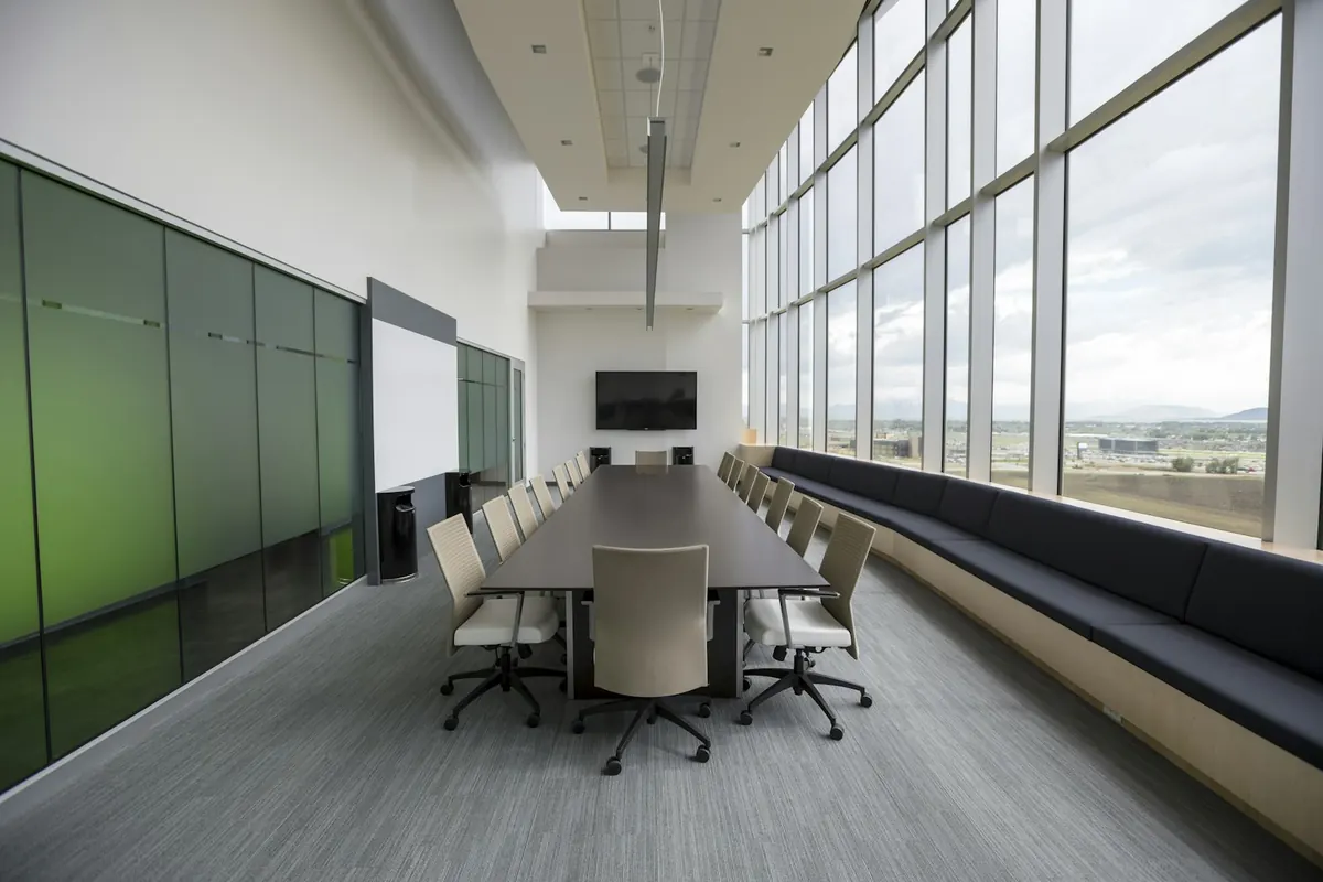 Boardroom table with chairs by floor-to-ceiling windows