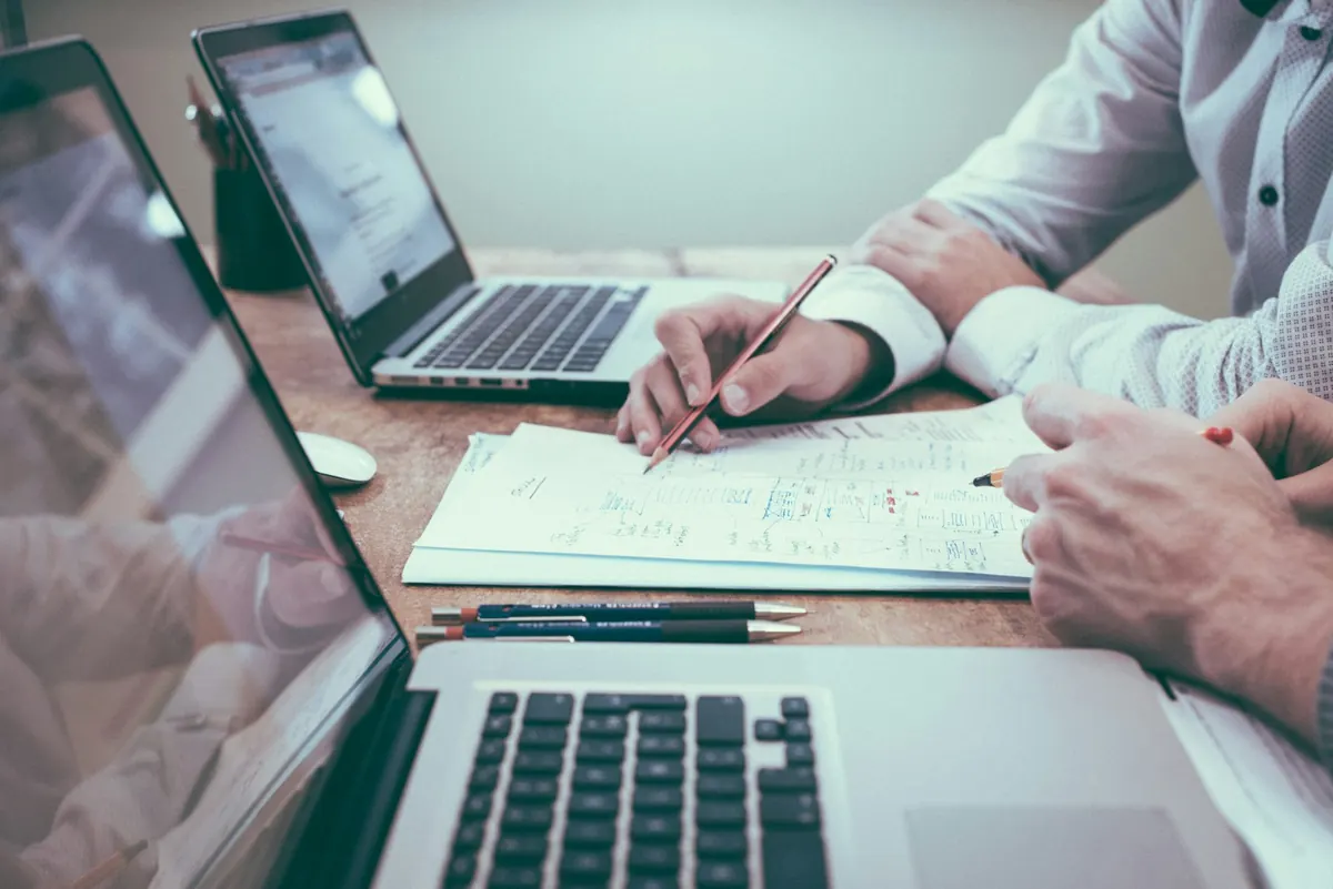 Two professionals working through documents and forecasts at a desk